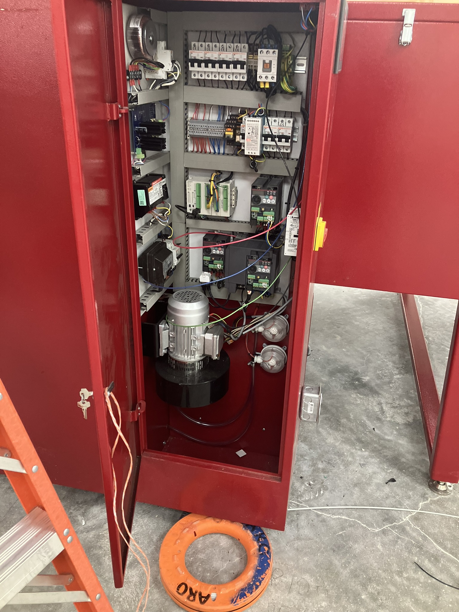 Electrician wearing gloves using a screwdriver to install a wall electrical outlet with a digital multimeter and tools on the counter.